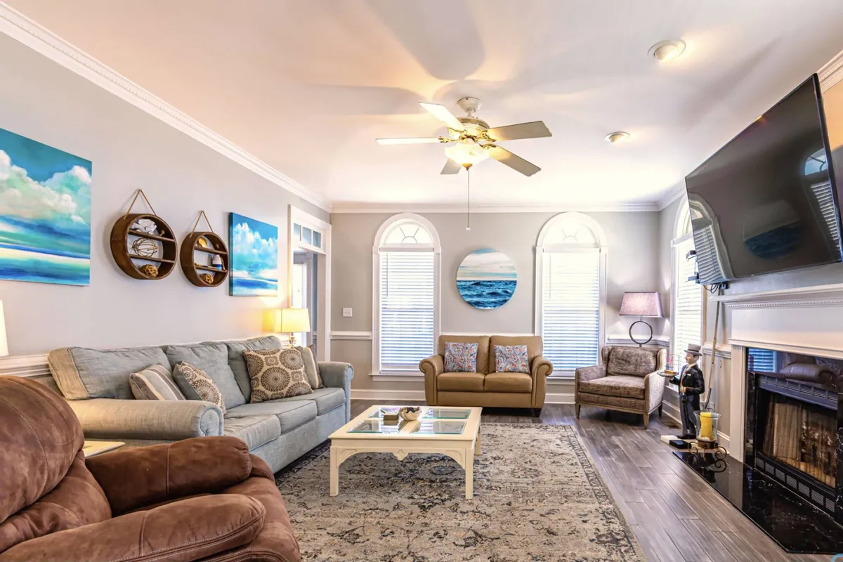 A spacious, inviting living room with plush seating arranged around a coffee table. Armchairs and a sofa provide ample space for socializing or lounging, and there's tasteful artwork on the walls and a cozy fireplace. The setup is perfect for gatherings and relaxation, capturing the vibe of a comfortable, communal living space.