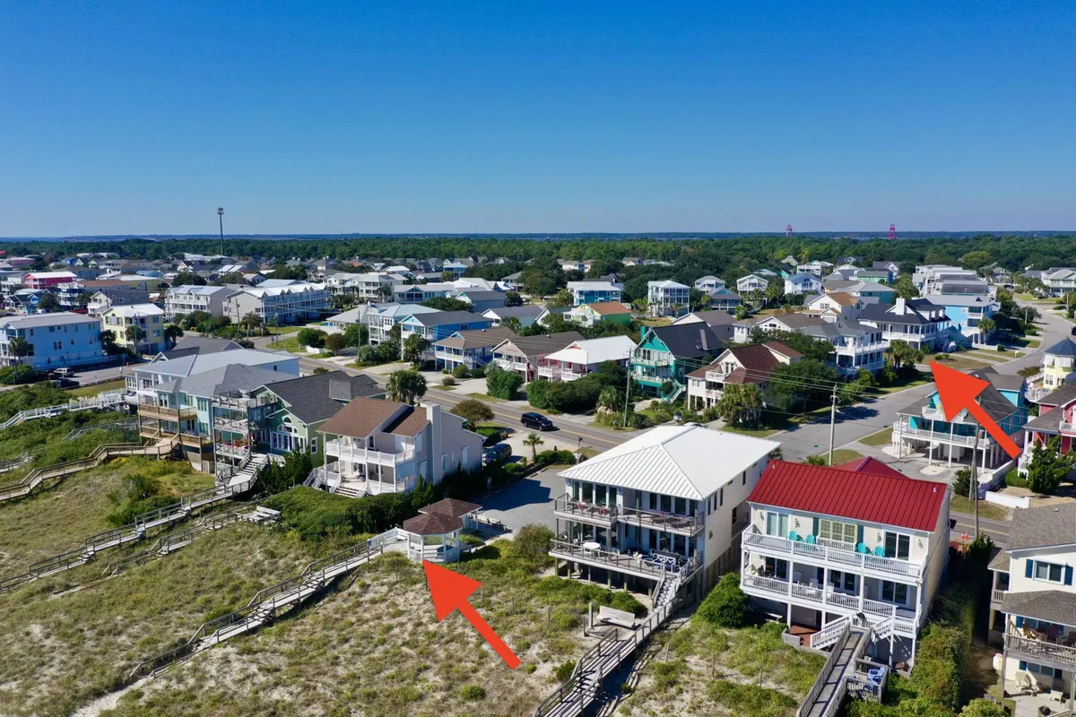 This image depicts beachfront properties lined up along the shore, with boardwalks connecting colorful houses. The scene suggests outdoor spaces ideal for gatherings, relaxation, and family fun, with the ocean and sand just steps away.