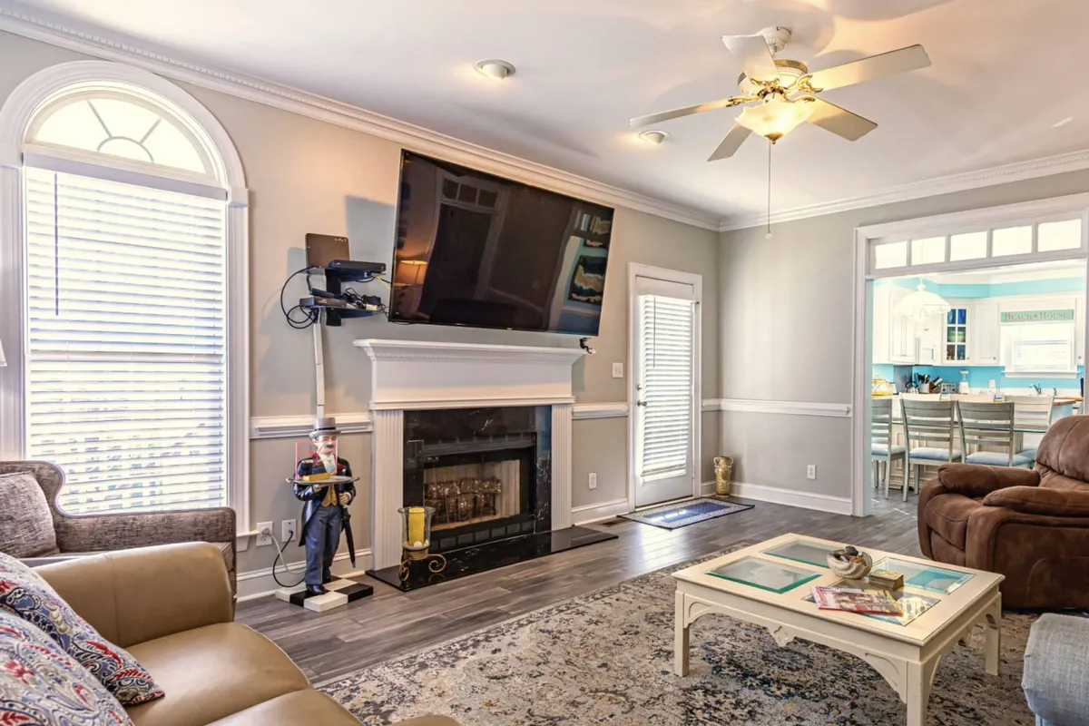 A warm and inviting living room featuring a plush sofa, fireplace, entertainment center, and a decorative rug. The space is perfect for gatherings or relaxing, and the sofa can be used as an extra pullout bed for guests.