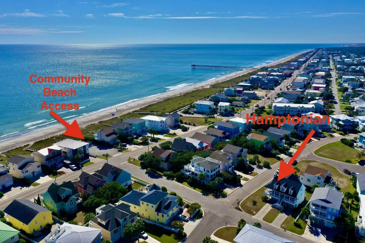 A scenic view of the community’s private beach access, the Hamptonian house in the background, and the nearby ocean. The image captures the proximity to the beach and the allure of daily coastal adventures.